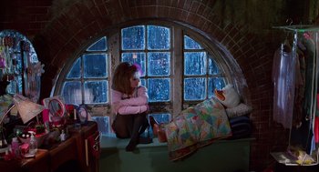 Movie still from “Howard the Duck” (1986), directed by Willard Huyck – A woman sitting on the floor next to a window; Wide shot, High angle