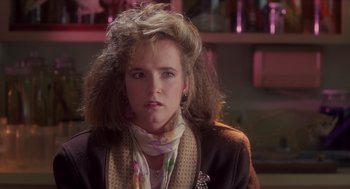 Movie still from “Howard the Duck” (1986), directed by Willard Huyck – A young woman with long hair wearing a jacket and a scarf; Close Up shot, Over the shoulder angle