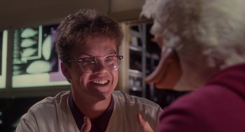 Movie still from “Howard the Duck” (1986), directed by Willard Huyck – A man with glasses and a white shirt is talking to another man; Close Up shot, Low angle