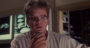 Movie still from “Howard the Duck” (1986), directed by Willard Huyck – A man with glasses is holding a cell phone; Close Up shot, Low angle