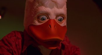 Movie still from “Howard the Duck” (1986), directed by Willard Huyck – A person wearing a duck mask and a red jacket; Extreme Close Up shot, Low angle
