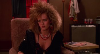 Movie still from “Howard the Duck” (1986), directed by Willard Huyck – A woman sitting in front of a wall with a big hair wig; Close Up shot, Low angle