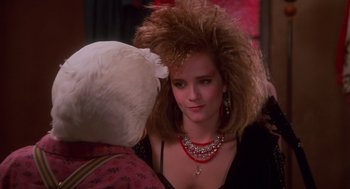 Movie still from “Howard the Duck” (1986), directed by Willard Huyck – A woman with a big messy hair style and a red necklace; Close Up shot, Over the shoulder angle