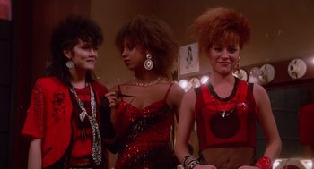 Movie still from “Howard the Duck” (1986), directed by Willard Huyck – A group of women standing next to each other in a room; Medium shot, Low angle