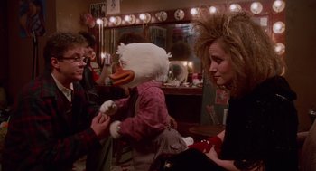 Movie still from “Howard the Duck” (1986), directed by Willard Huyck – A person in a chicken costume and a woman in a wig; Medium shot, Over the shoulder angle