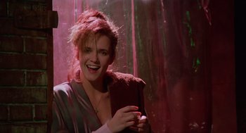 Movie still from “Howard the Duck” (1986), directed by Willard Huyck – A woman with red hair is smiling for the camera; Medium shot, Low angle