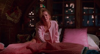 Movie still from “Howard the Duck” (1986), directed by Willard Huyck – A woman sitting on top of a bed in a pink robe; Medium shot, Low angle