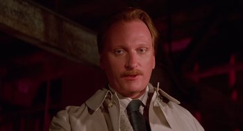 Movie still from “Howard the Duck” (1986), directed by Willard Huyck – A person wearing a suit and tie; Close Up shot, Low angle