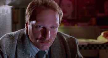 Movie still from “Howard the Duck” (1986), directed by Willard Huyck – A person wearing a suit and tie; Close Up shot, Low angle