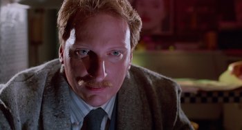 Movie still from “Howard the Duck” (1986), directed by Willard Huyck – A person wearing a suit and tie; Close Up shot, Low angle