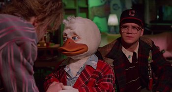 Movie still from “Howard the Duck” (1986), directed by Willard Huyck – A person wearing a duck mask in a room; Medium shot, Over the shoulder angle