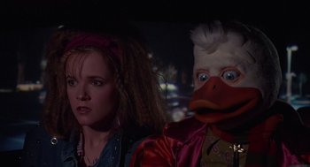 Movie still from “Howard the Duck” (1986), directed by Willard Huyck – A woman standing next to a man with a duck mask; Close Up shot, Low angle