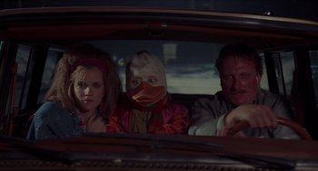 Movie still from “Howard the Duck” (1986), directed by Willard Huyck – A group of people sitting in the back of a car; Medium shot, Low angle