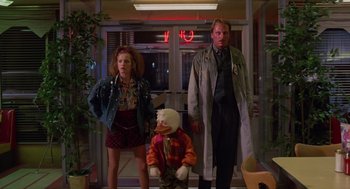 Movie still from “Howard the Duck” (1986), directed by Willard Huyck – A group of people standing next to each other in front of a building; Wide shot, Low angle