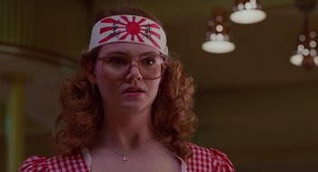 Movie still from “Howard the Duck” (1986), directed by Willard Huyck – A woman wearing a headband and glasses in front of a wall; Close Up shot, Low angle