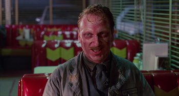 Movie still from “Howard the Duck” (1986), directed by Willard Huyck – A man in a dark shirt and a tie; Medium shot, Low angle