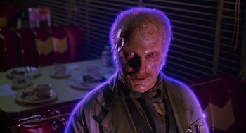 Movie still from “Howard the Duck” (1986), directed by Willard Huyck – A man with a face covered in purple light; Close Up shot, Low angle