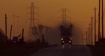 Movie still from “Howard the Duck” (1986), directed by Willard Huyck – A truck driving down a road near power lines; Extreme Wide shot, Low angle