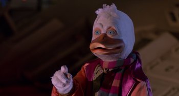 Movie still from “Howard the Duck” (1986), directed by Willard Huyck – A person in a duck costume holding a cigarette; Close Up shot, Low angle