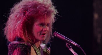 Movie still from “Howard the Duck” (1986), directed by Willard Huyck – A woman with pink hair is singing into a microphone; Close Up shot, Low angle