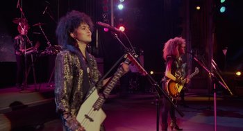Movie still from “Howard the Duck” (1986), directed by Willard Huyck – A group of people that are on a stage; Wide shot, Low angle