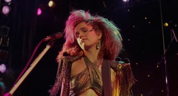 Movie still from “Howard the Duck” (1986), directed by Willard Huyck – A woman with pink hair is singing into a microphone; Close Up shot, Low angle