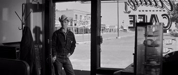 Movie still from “Hud” (1963), directed by Martin Ritt – A black and white photo of a man standing in front of a store window; Wide shot, Over the shoulder angle