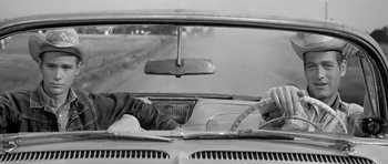 Movie still from “Hud” (1963), directed by Martin Ritt – Two people in the back seat of a car driving down a road; Medium shot, Low angle