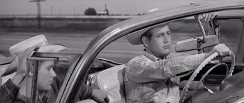 Movie still from “Hud” (1963), directed by Martin Ritt – A black and white photo of a man driving a car; Medium shot, Over the shoulder angle