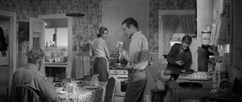 Movie still from “Hud” (1963), directed by Martin Ritt – A man and a woman standing in a kitchen next to a stove; Medium shot, Low angle