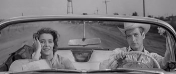 Movie still from “Hud” (1963), directed by Martin Ritt – A woman and a man driving a car down a road; Medium shot, Low angle