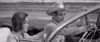 Movie still from “Hud” (1963), directed by Martin Ritt – A man wearing a cowboy hat sitting in the driver's seat of a car; Medium shot, Over the shoulder angle