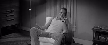 Movie still from “Hud” (1963), directed by Martin Ritt – A black and white photo of a man sitting in a chair; Medium shot, Low angle