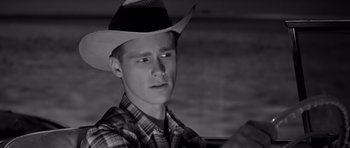 Movie still from “Hud” (1963), directed by Martin Ritt – A young man wearing a cowboy hat in a black and white photo; Close Up shot, Over the shoulder angle
