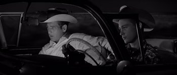Movie still from “Hud” (1963), directed by Martin Ritt – Two men sitting in the drivers seat of a car; Medium shot, Over the shoulder angle