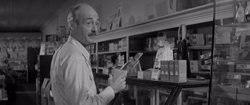 Movie still from “Hud” (1963), directed by Martin Ritt – An older man holding a cell phone while standing in a store; Close Up shot, Low angle