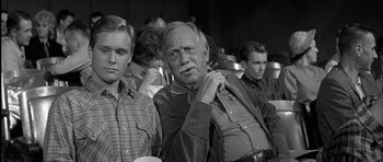 Movie still from “Hud” (1963), directed by Martin Ritt – An older man standing in front of a group of young men; Medium shot, Over the shoulder angle