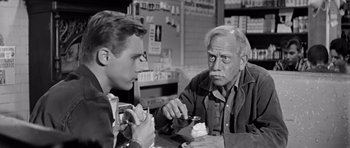 Movie still from “Hud” (1963), directed by Martin Ritt – Two men sitting at a table with a plate of food; Medium shot, Over the shoulder angle