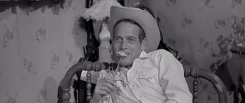 Movie still from “Hud” (1963), directed by Martin Ritt – A man wearing a cowboy hat and holding a flower; Close Up shot, High angle