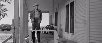 Movie still from “Hud” (1963), directed by Martin Ritt – An older man standing on a porch rail; Wide shot, Low angle