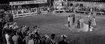 Movie still from “Hud” (1963), directed by Martin Ritt – A group of people standing in the dirt at an event; Wide shot, High angle