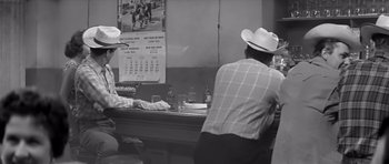 Movie still from “Hud” (1963), directed by Martin Ritt – Two men in cowboy hats are sitting at a bar; Medium shot, Over the shoulder angle