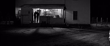 Movie still from “Hud” (1963), directed by Martin Ritt – Two people standing in front of a building at night; Extreme Wide shot, Over the shoulder angle