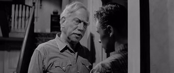 Movie still from “Hud” (1963), directed by Martin Ritt – An older man talking to a younger man in a black and white photo; Medium shot, Over the shoulder angle