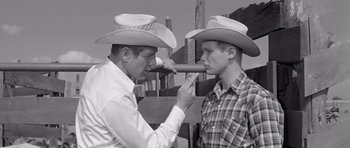 Movie still from “Hud” (1963), directed by Martin Ritt – Two men in cowboy hats one of which has a cigar in his mouth; Medium shot, Over the shoulder angle