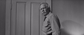 Movie still from “Hud” (1963), directed by Martin Ritt – An older man standing in front of a door; Medium shot, Low angle