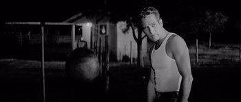 Movie still from “Hud” (1963), directed by Martin Ritt – Black and white photograph of a man standing in front of a building; Medium shot, Low angle