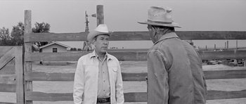 Movie still from “Hud” (1963), directed by Martin Ritt – Two men in cowboy hats standing next to each other in a field; Medium shot, Over the shoulder angle