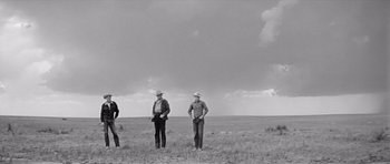 Movie still from “Hud” (1963), directed by Martin Ritt – A group of men standing on top of a grass covered field; Wide shot, Low angle