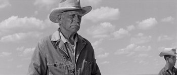 Movie still from “Hud” (1963), directed by Martin Ritt – An older man wearing a cowboy hat in front of a cloudy sky; Medium shot, Low angle